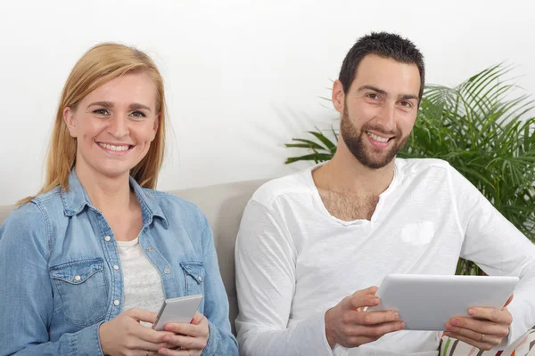Gelukkige jonge paar met behulp van de tablet en telefoon — Stockfoto