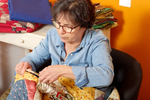 Vrouw naaien voor afwerking een quilt. — Stockfoto