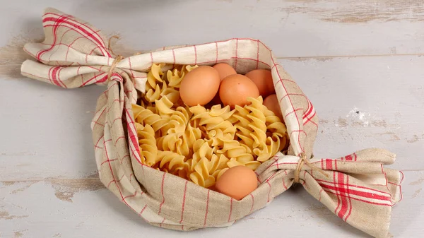Pasta in a towel on a wooden table — Stock Photo, Image