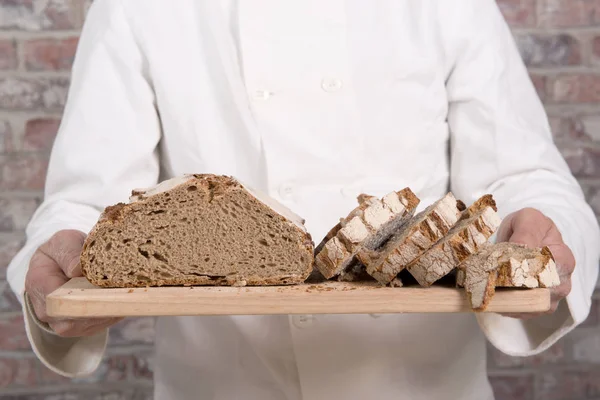 Руки пекаря со свежим хлебом на столе — стоковое фото
