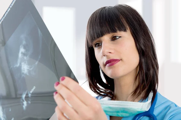 Young female doctor with stethoscope looking at patients x-ray — Stock Photo, Image