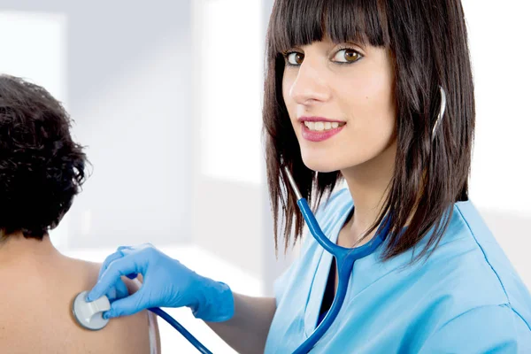 Female doctor examines a patient with a stethoscope — Stock Photo, Image