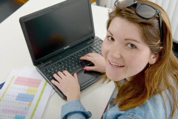 Симпатичная молодая бизнесвумен, работающая на ноутбуке в офисе — стоковое фото