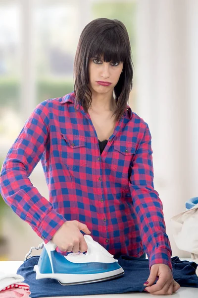 Unhappy young beautiful woman ironing clothes — Stock Photo, Image