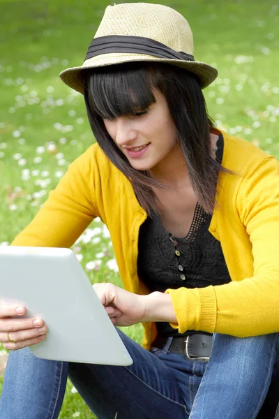 Chica morena joven con una tableta en el parque, fuera — Foto de Stock