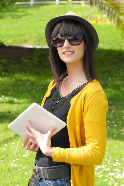 Chica morena joven con una tableta en el parque, fuera — Foto de Stock