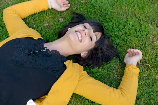 Jonge brunette meisje liggend in het gras — Stockfoto