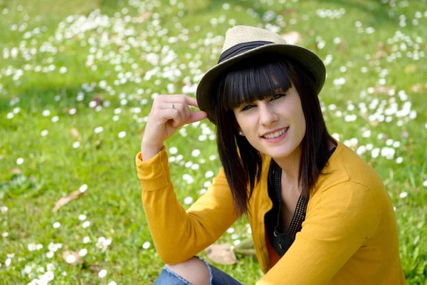 Young brunette girl sitting on  grass in park, outdoors — Stock Photo, Image