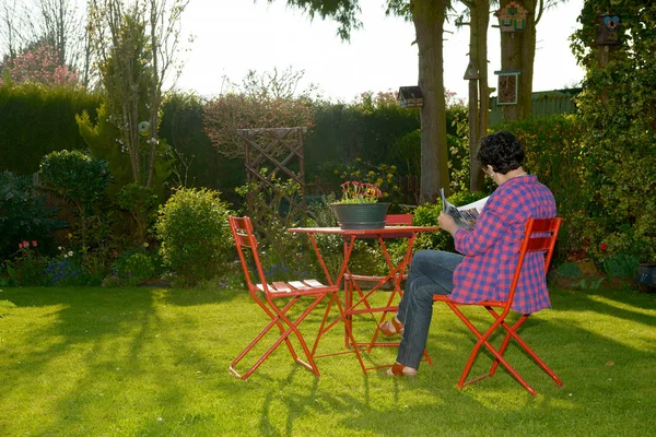 Mature woman reading a book in the garden — Stock Photo, Image