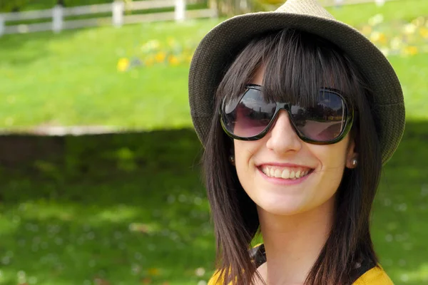 Portrét mladé brunetka s letní klobouk v parku — Stock fotografie