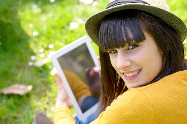 Unga brunett tjej med en tablett i park, utanför — Stockfoto
