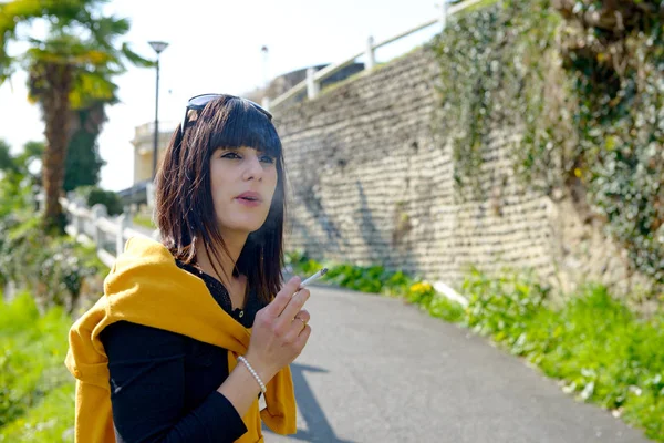 Young brunette woman smoking  cigarette outside — Stock Photo, Image