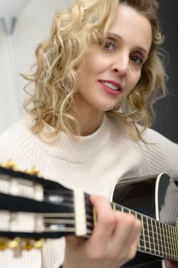 Genç sarışın kadın akustik gitar çalmak
