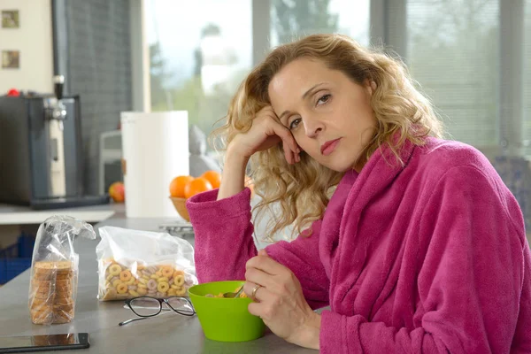 Unga blonda kvinnan äter spannmål på morgonen — Stockfoto