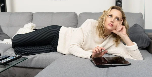 Blondine entspannt auf dem Sofa mit Tablet-Computer — Stockfoto