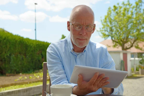 Mature man use tablet . Sitting in the garden — Stock Photo, Image