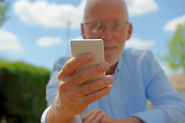 Starszy człowiek za pomocą telefonu komórkowego, poza — Zdjęcie stockowe