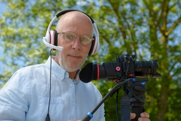 Mannen med hörlurar, med en dslr-kamera — Stockfoto