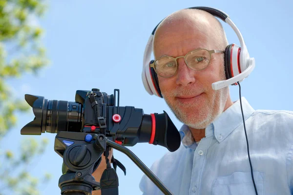 Homem com fones de ouvido, usando uma câmera dslr — Fotografia de Stock
