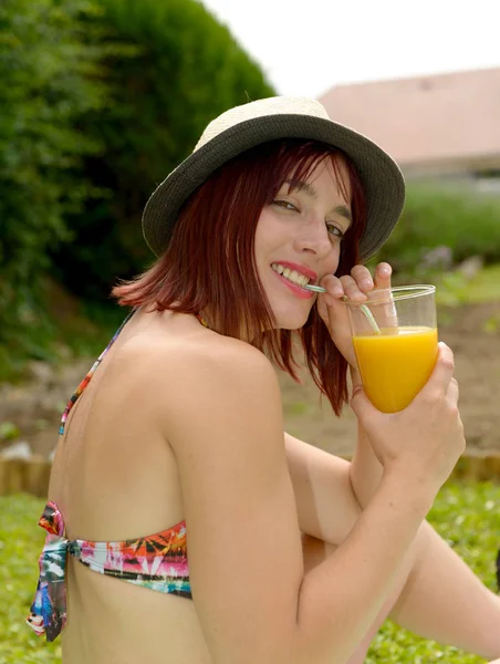 Bella ragazza con cappello estivo, bere succo d'arancia — Foto Stock