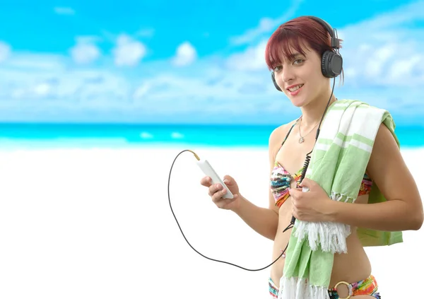 Красивая девушка слушает музыку со своим смартфоном на пляже — стоковое фото