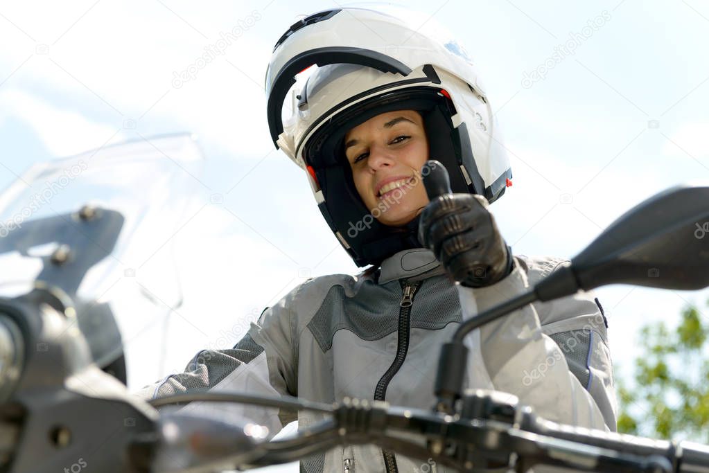  girl sits on a motorcycle and has a helmet on his head