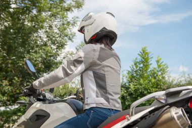 Kız bir motosiklet üzerinde oturur ve kafasında kask vardır