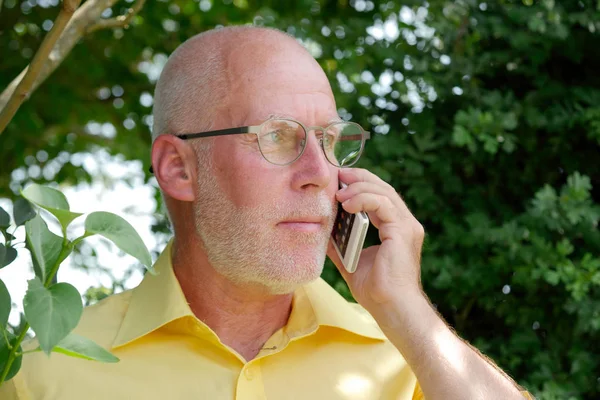 Gesunder Senior telefoniert im Garten — Stockfoto