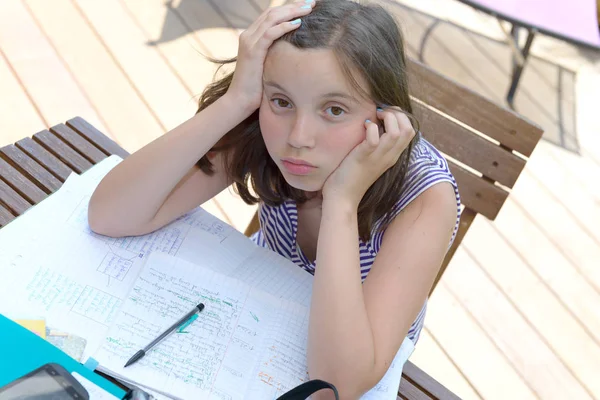 无聊的十几岁的女孩正在做她的作业 — 图库照片
