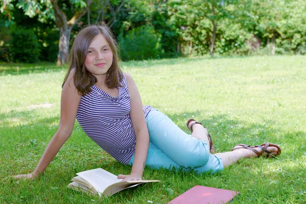 Bela adolescente fêmea lendo um livro na grama — Fotografia de Stock