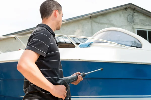 Young man cleaning boat with high pressure water — Stock Photo, Image