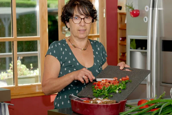 Sonriente mujer morena de mediana edad preparando la comida — Foto de Stock