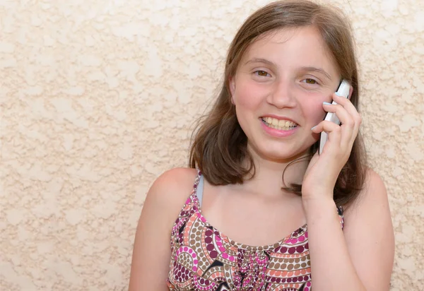 Sonriendo pre adolescente chica llamando en el teléfono inteligente, al aire libre —  Fotos de Stock