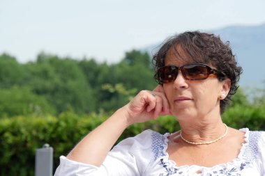 Gülümseyen bahçede evde oturan orta yaş kadın portresi