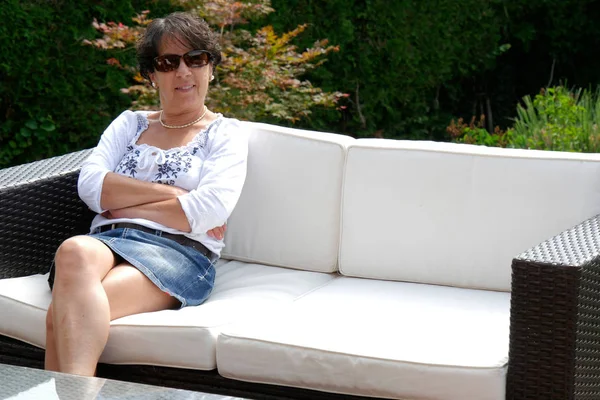 Retrato de una mujer sonriente de mediana edad sentada en el jardín en casa —  Fotos de Stock