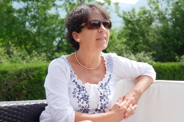 Retrato de mulher de meia-idade sorridente sentada no jardim em casa — Fotografia de Stock