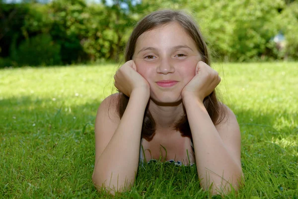 Prachtige pre tienermeisje leggen in gras — Stockfoto