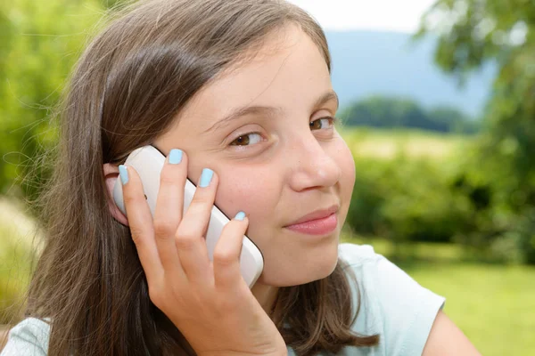 Sonriendo pre adolescente chica llamando en el teléfono inteligente, al aire libre — Foto de Stock