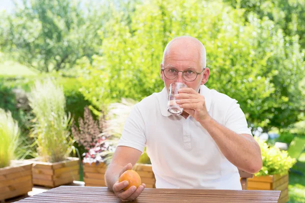 Homme mûr boire un verre d'eau sur la terrasse — Photo