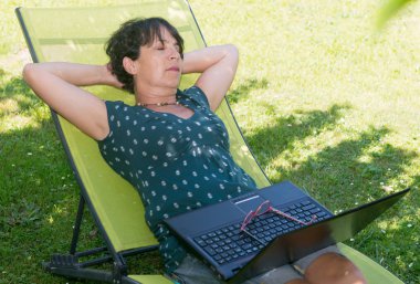 Bahçe şezlong üzerinde rahatlatıcı mutlu olgun kadın