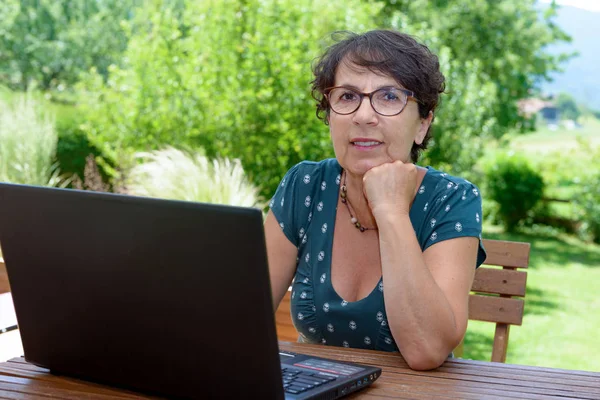Modern casual woman sitting at garden with laptop — Stock Photo, Image