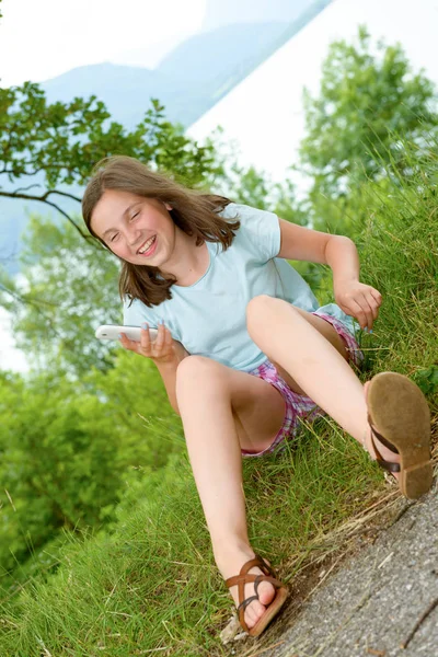 Pre teenager mädchen texten auf handy, outdoor — Stockfoto