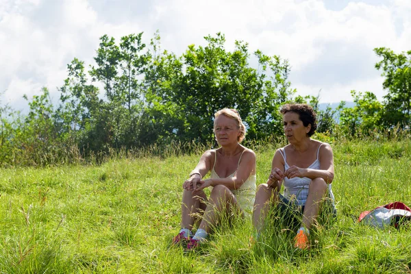 Dinlenme ve otların arasında oturan iki kadın