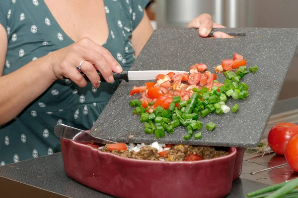 Женщина режет помидоры ножом, на тарелке — стоковое фото