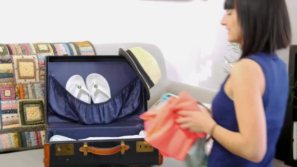 Jeune femme emballer ses vêtements dans une valise ouverte, préparation pour les vacances ou Voyage — Video