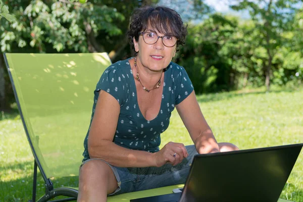 Modern casual kadın Garden'da laptop ile oturuyordu