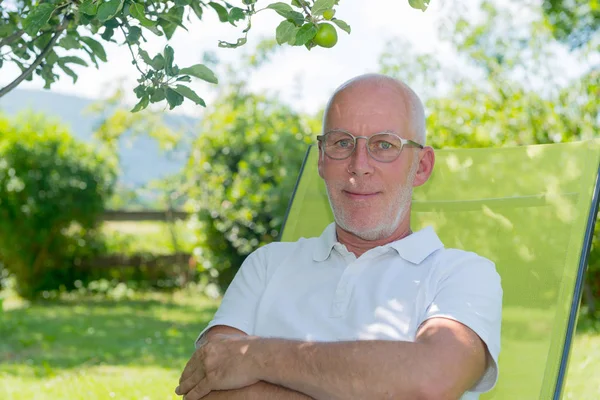 Portret van senior man die lacht in de tuin — Stockfoto