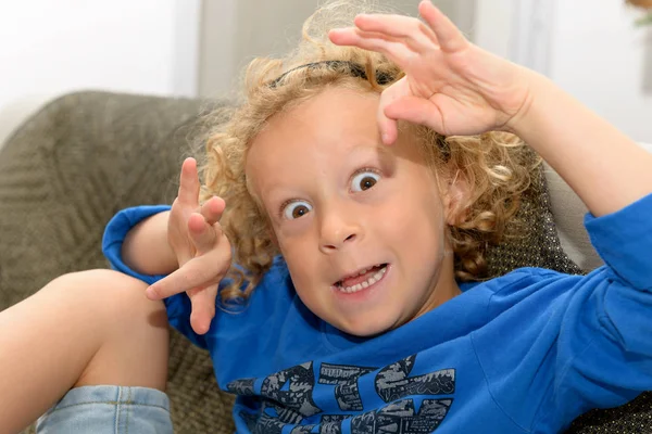 Niño pequeño con el pelo rubio y rizado haciendo caras —  Fotos de Stock