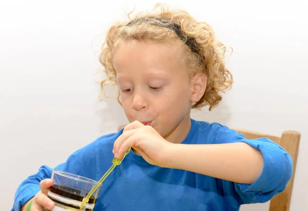 Mignon petit garçon boit du jus rouge en utilisant de la paille — Photo