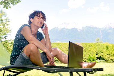 smartphone kullanarak Bahçe güverte sandalyede oturan kadın